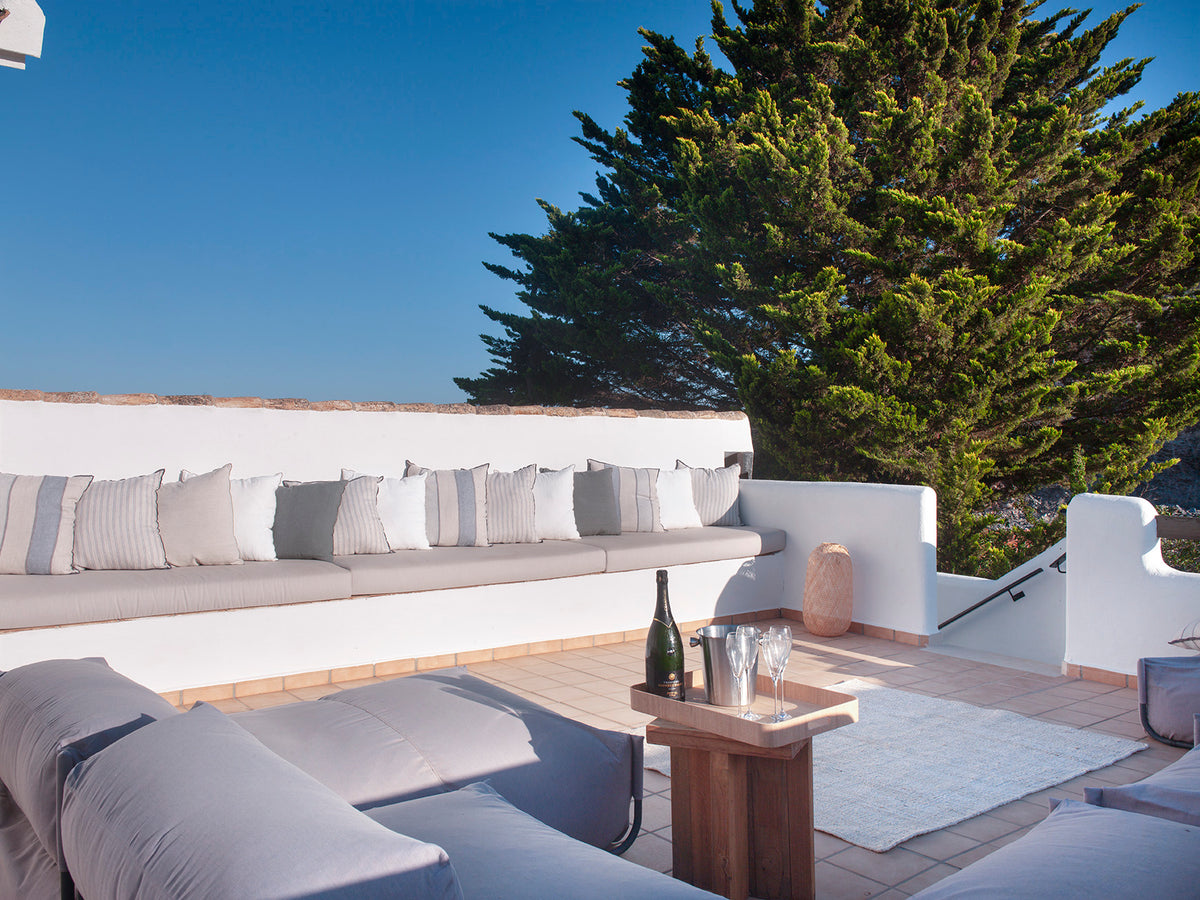 Terraza chill out con banco de obra blanco, cojines y mesa de madera